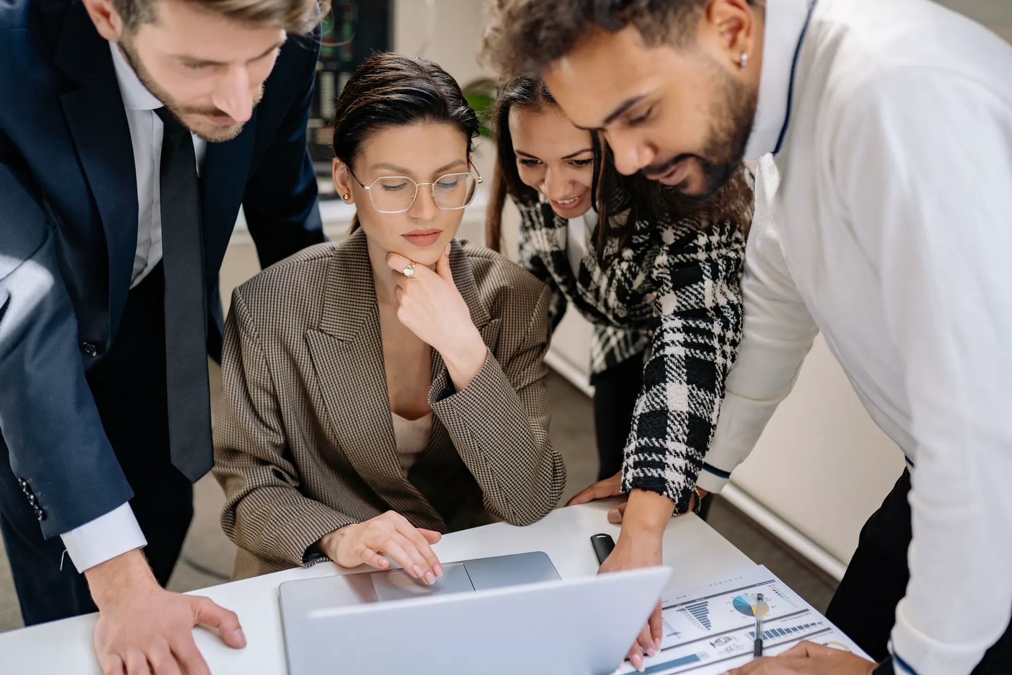A professional team collaborating around a laptop in a modern office